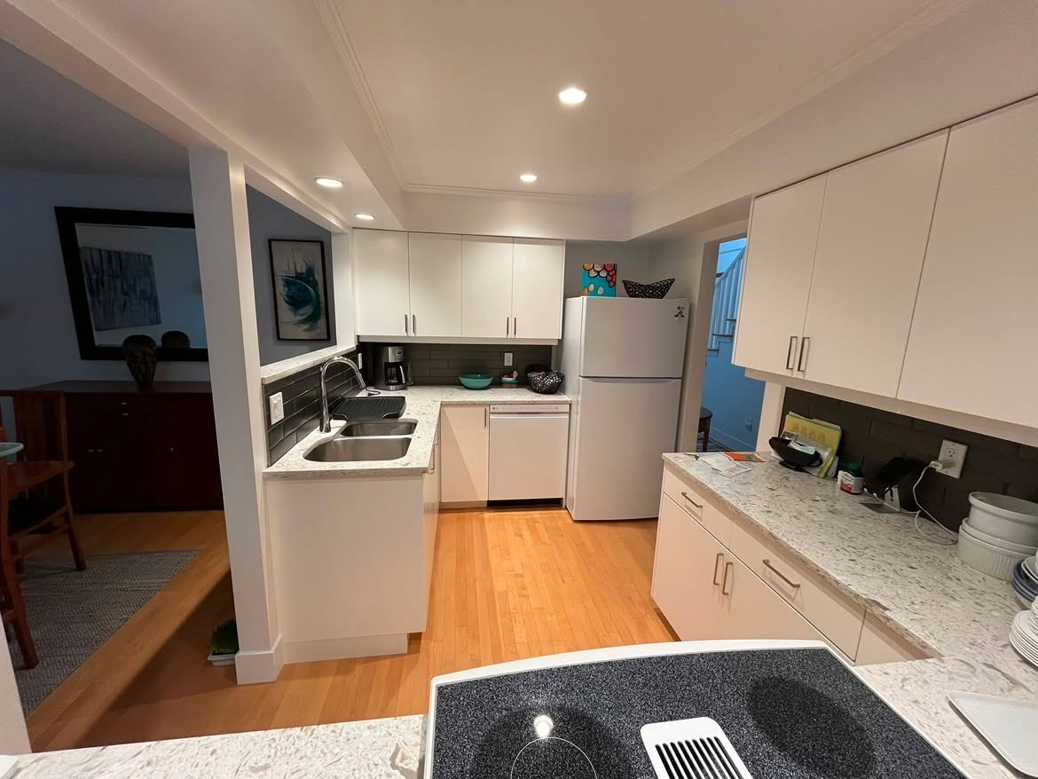 Freshly cleaned kitchen with white cabinets and wood floors